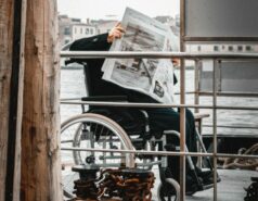 a man in a wheel chair reading a newspaper